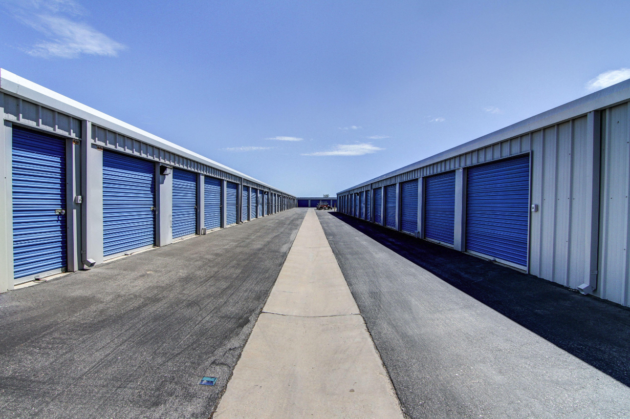 Rows of drive-up storage units with blue roll-up doors at The Yard Mini Storage in Auburn, Illinois